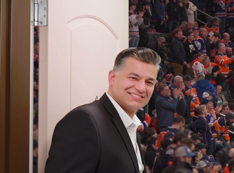 Man at open hotel door showing Oilers crowd behind it